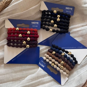 Close-up of elastic hair ties with gold beads in assorted colors on linen background