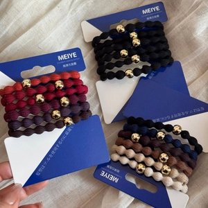 Detail of high-elasticity ribbed hair ties with decorative gold beads on display cards