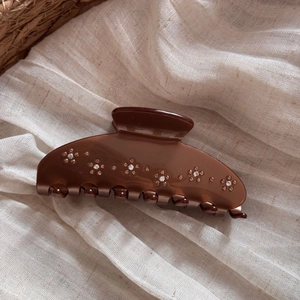 Close-up of amber brown acetate hair claw clip with sparkling rhinestone flower patterns