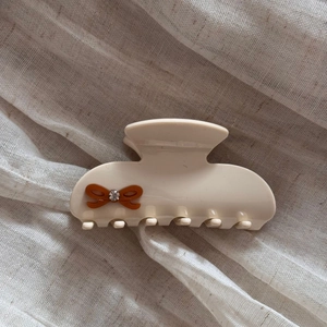 Close-up of beige acetate hair claw with brown bow and sparkling crystal detail