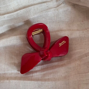 Close-up of a glossy red bow hair claw clip with golden Barrette La France text detail