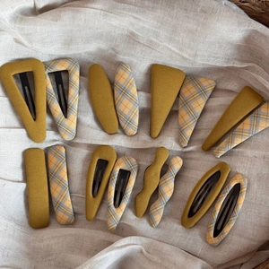 Set of fabric covered plaid hair clips in yellow and blue patterns on white fabric