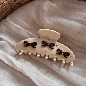 Detail view of acetate hair claw clip with diamond bow accents and polished finish