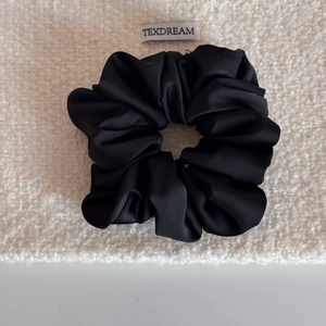 Détail d'un chouchou en satin noir avec texture lisse et plis élégants sur tissu