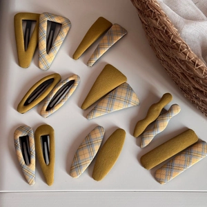 Detail of fabric-wrapped hair clips in yellow and blue plaid with various geometric shapes