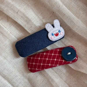 Detailed view of handmade plaid and denim bunny hair clips set on fabric background