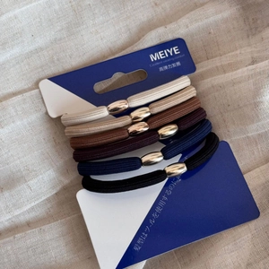 Detail view of six high-elastic woven hair ties in earth tones on branded display card