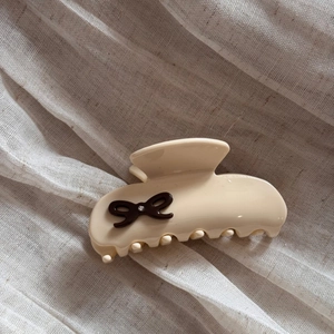 Detail of cream acetate hair claw clip with dark brown bow and sparkling rhinestone