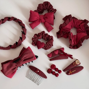 Dettaglio di accessori per capelli rosso scuro in velluto con fiocchi, clip ed elastici