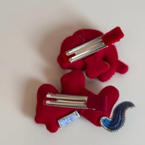 Dettaglio di fermagli per capelli in peluche rosso con clip in argento e ricamo