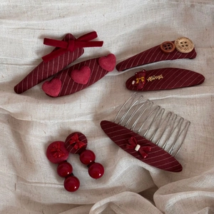 Dettaglio di un set di fermagli per capelli rossi a righe con orsetti e cuori