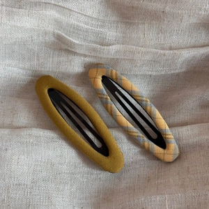 Detail view of mustard yellow and plaid fabric wrapped retro metal snap hair clips