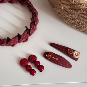 Dettaglio dei fermagli per capelli a righe bordeaux con fiocco e cerchietto con orso