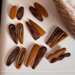 Detail of assorted fabric hair clips in caramel orange and brown plaid patterns