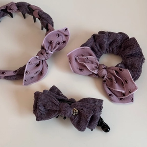Three-piece purple hair accessories set featuring paisley bow headband, scrunchie, and claw clip