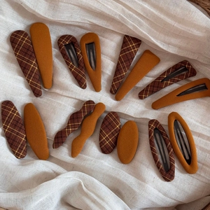 Close-up of yellow and plaid fabric hair clips in various shapes on soft white linen