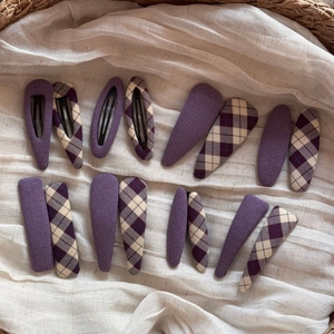 Detailed macro view of purple fabric-wrapped snap hair clips in solid and plaid patterns