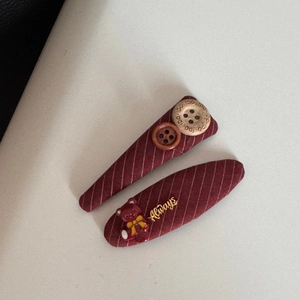 Dettaglio di fermagli per capelli a righe rosse con orsetto e bottoni in legno