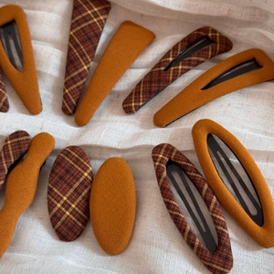 Detail of fabric wrapped BB hair clips in plaid and solid orange patterns on linen