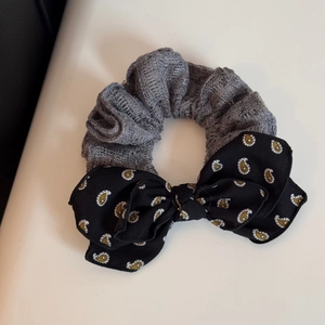 Detailed view of grey textured scrunchie with a black paisley pattern bow accessory