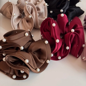Close-up of assorted satin hair scrunchies with white pearls in multiple elegant colors