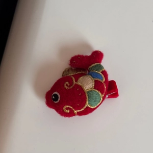Dettaglio di un fermaglio per capelli carpa rossa ricamata con filo dorato e arte