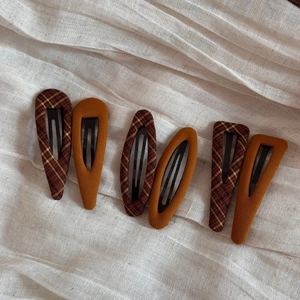 Close-up of 6-piece fabric snap clips featuring brown plaid and mustard yellow styles