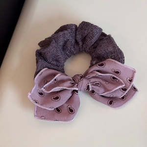 Detail of purple pleated mesh headband with large double-layered paisley bow