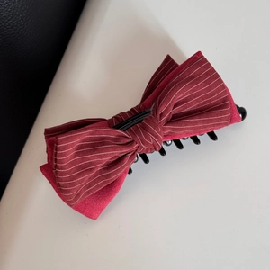 Dettaglio del fermaglio per capelli a fiocco rosso con strisce in tessuto e clip nera