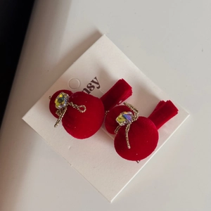 Dettaglio di fermagli per capelli in velluto rosso con fiocchi dorati e cristalli