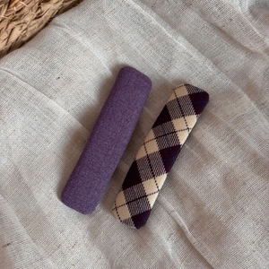 Detail of two purple fabric hair clips with plain and diamond checkered weave patterns
