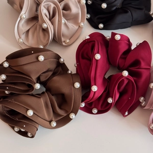 Close-up of assorted satin scrunchies with pearls in brown, burgundy, and beige colors