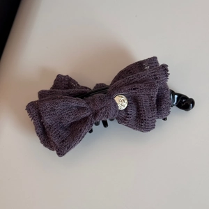 Close-up of dark purple lace bow hair claw with elegant engraved metal button detail