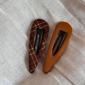 Detail of fabric plaid and yellow bb hair clips on rustic linen textile background