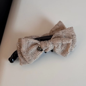 Detailed macro view of cream lace double bow hair clip with engraved metal plate