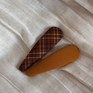 Detail of plaid and mustard yellow fabric BB hair clips on soft linen background