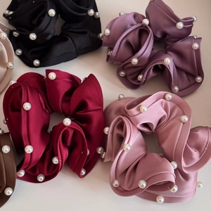 Detail of assorted satin scrunchies with elegant faux pearl embellishments and ruffled edges