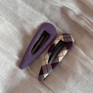 Detail of two purple fabric-wrapped BB hair clips with solid and argyle patterns