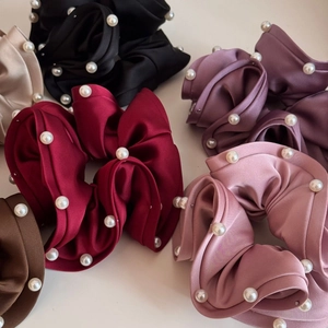 Detailed macro view of satin scrunchies with white faux pearls in multiple colors