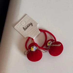 Dettaglio di elastici per capelli in velluto rosso con fiocco dorato e cristallo