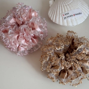 Detailed macro of pink and champagne satin hair scrunchies with lace and sequins