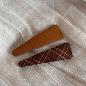 Detail of vintage fabric plaid hair clips in yellow and brown tones on beige linen