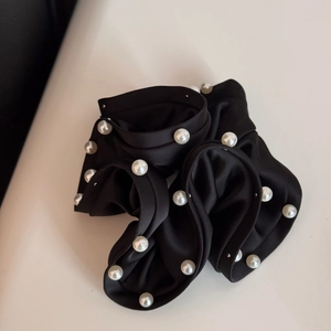 Close-up of black satin scrunchie with white pearl embellishments and elegant texture