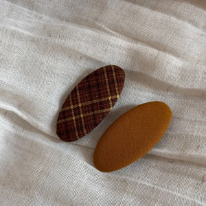 Detail of plaid and solid fabric wrapped oval BB hair clips on soft white gauze