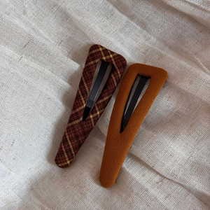 Detail of two vintage fabric-covered triangle hair clips in plaid and mustard tones