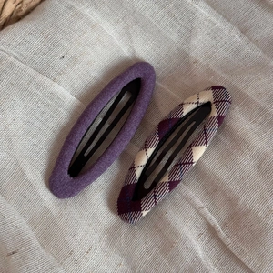 Detailed view of purple fabric and plaid pattern BB hair clips on linen cloth