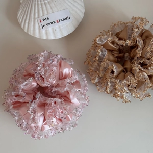 Detail of pink and gold sequined lace hair scrunchies with silk texture on beige background