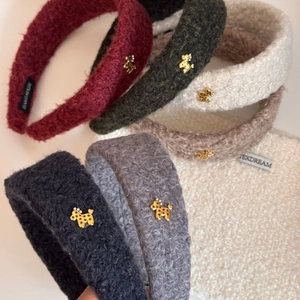 Close-up of fluffy bouclé headbands with golden poodle charms and handmade tags