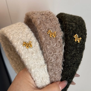 Close-up of three plush headbands with golden dog charms and star patterns on teddy fabric