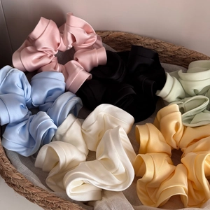 Elegant satin silk scrunchie set in assorted pastel colors presented in a woven basket
